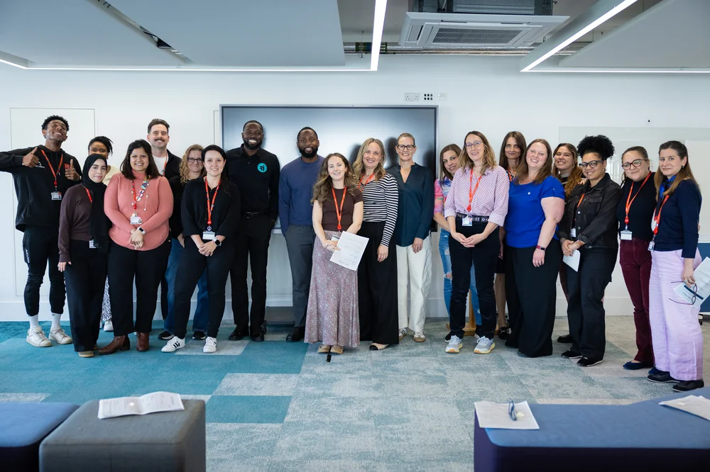 An LCG cohort standing together at the end of a training session, holding certificates for a group photograph.