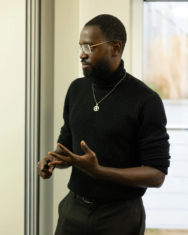 An LCG facilitator at the front of a training room, gesturing while a delegate looks on.